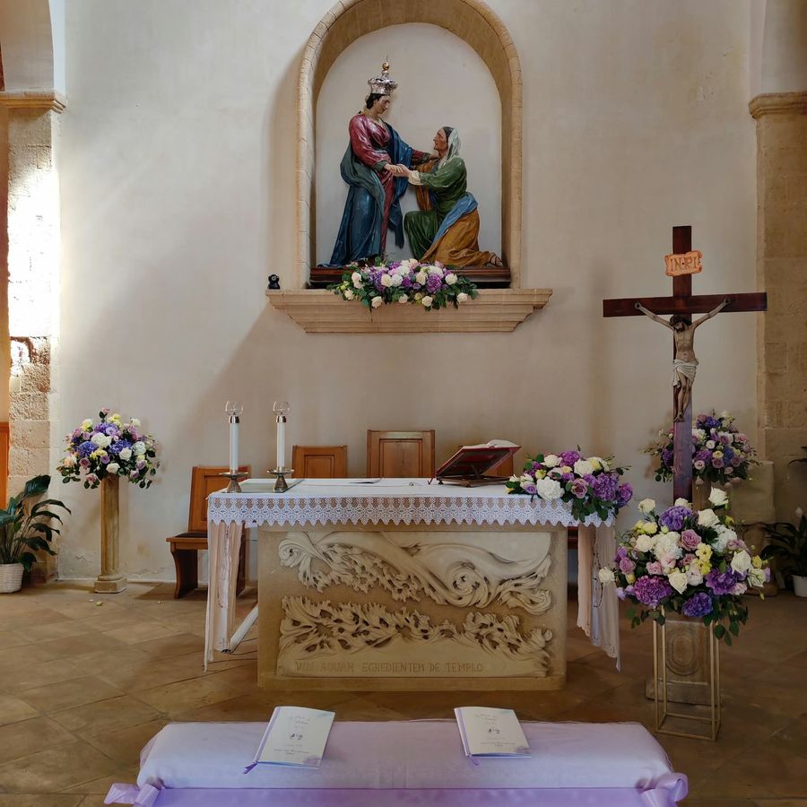 Addobbo floreale di chiesa con composizioni bianche e lilla sull'altare, sulle colonne e ai piedi del crocifisso, con inginocchiatoio per gli sposi
