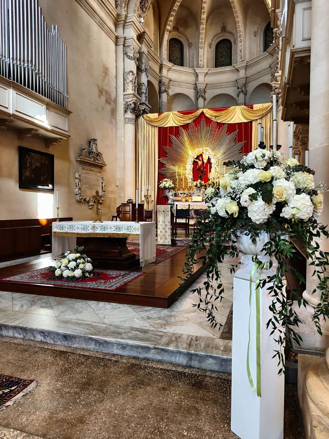 Addobbo di chiesa con grande vaso di rose e ortensie bianche su colonna e composizione bianca ai piedi dell'altare