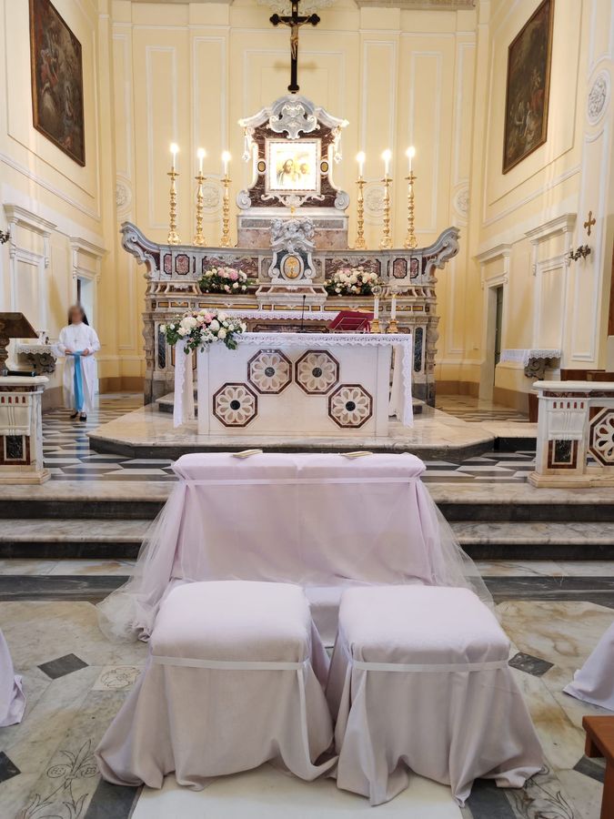 Allestimento di chiesa con composizioni di rose bianche e rosa sull'altare e inginocchiatoio per due rivestito di tessuto rosa e tulle